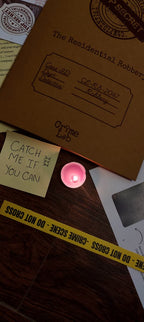 Case file labeled 'Residential Robbery' with a candle and crime scene tape on a wooden surface.