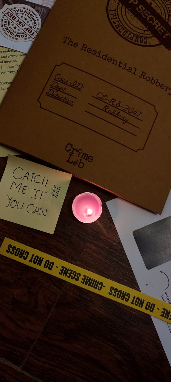 Case file labeled 'Residential Robbery' with a candle and crime scene tape on a wooden surface.