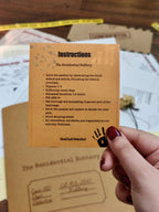 Instructions card for a mystery game held by a hand, with game materials in the background.